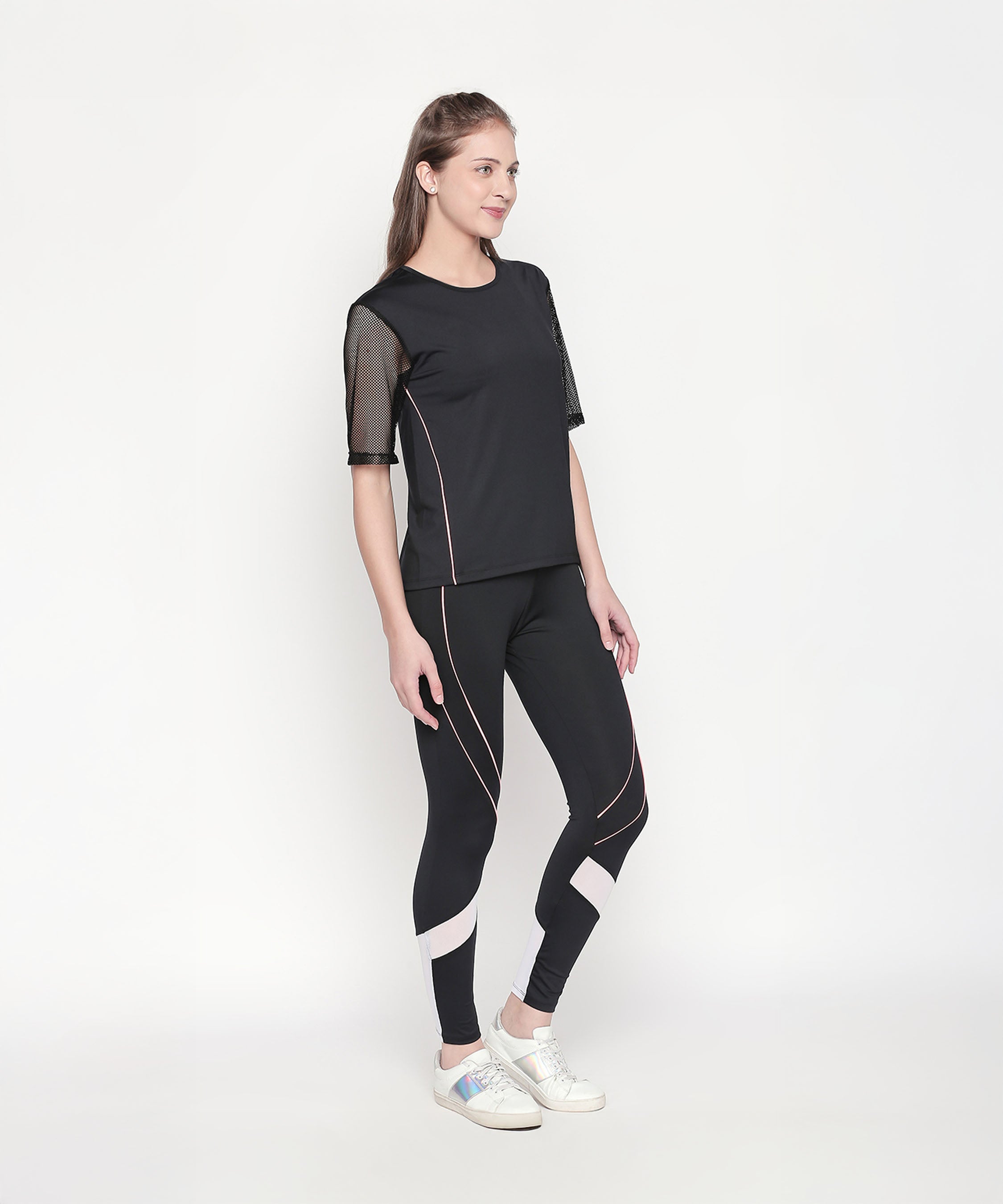 Woman wearing the Activewear Black Tracksuit with high-waisted leggings and mesh sleeves, paired with white sneakers, stands against a plain white background.