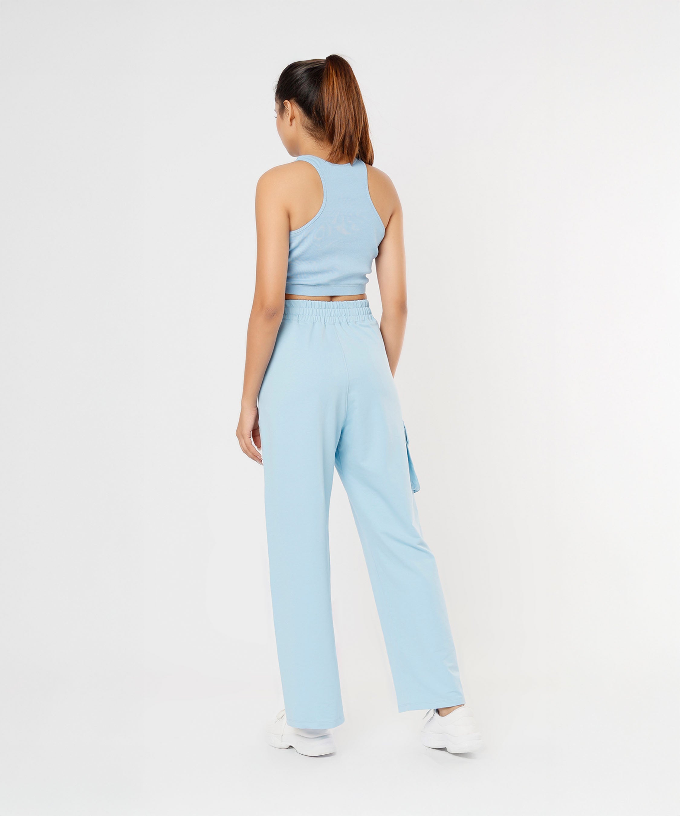 A woman models the Blossom Blue Set with Crop Top and matching pants, standing with her back to the camera in a white studio.