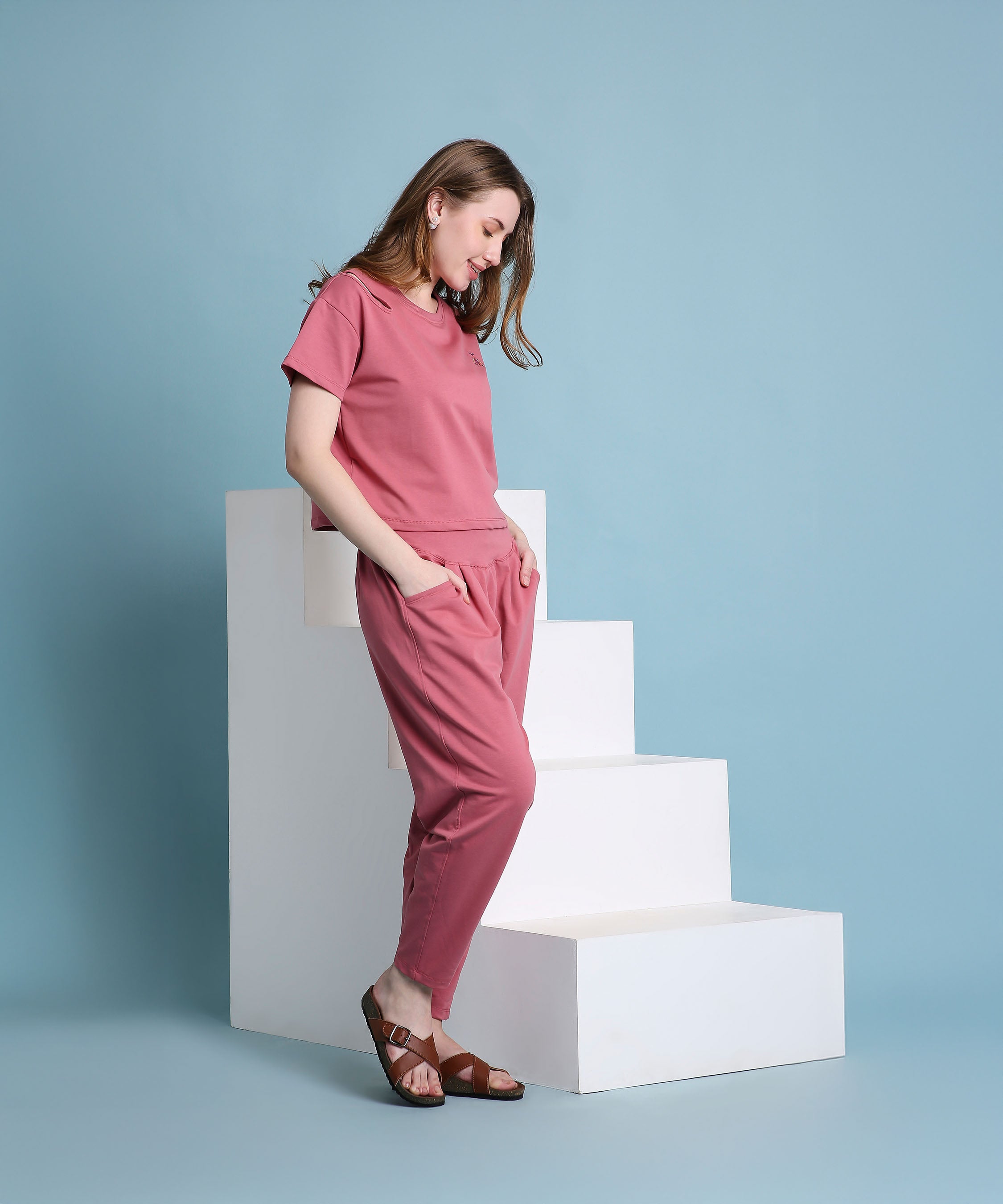 A woman wearing the Vintage Pink Knit Cord Set stands beside white steps against a light blue background.