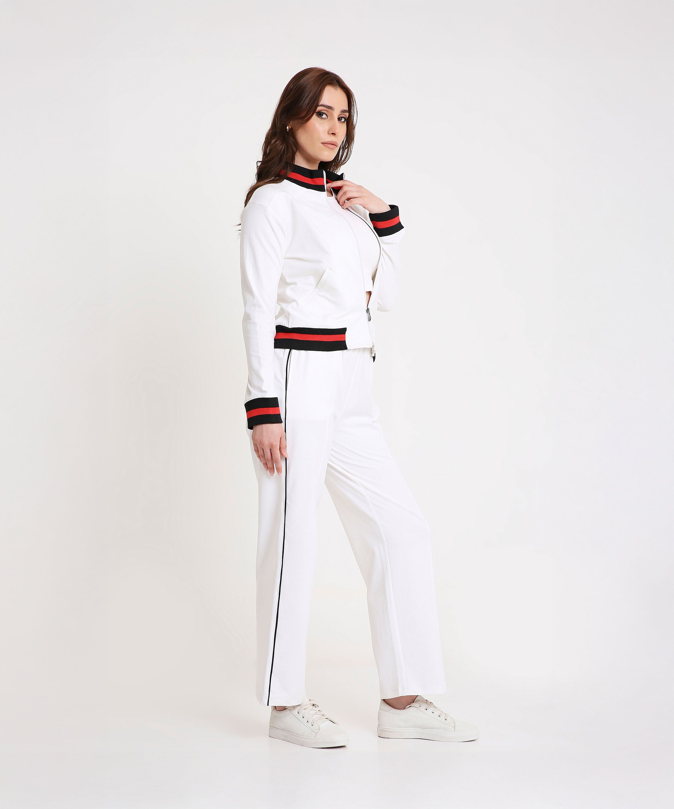A woman models the Two Piece Bold Contrast White Tracksuit, featuring black and red trim on soft cotton-blend fabric, styled with white sneakers for a modern sporty-chic look.