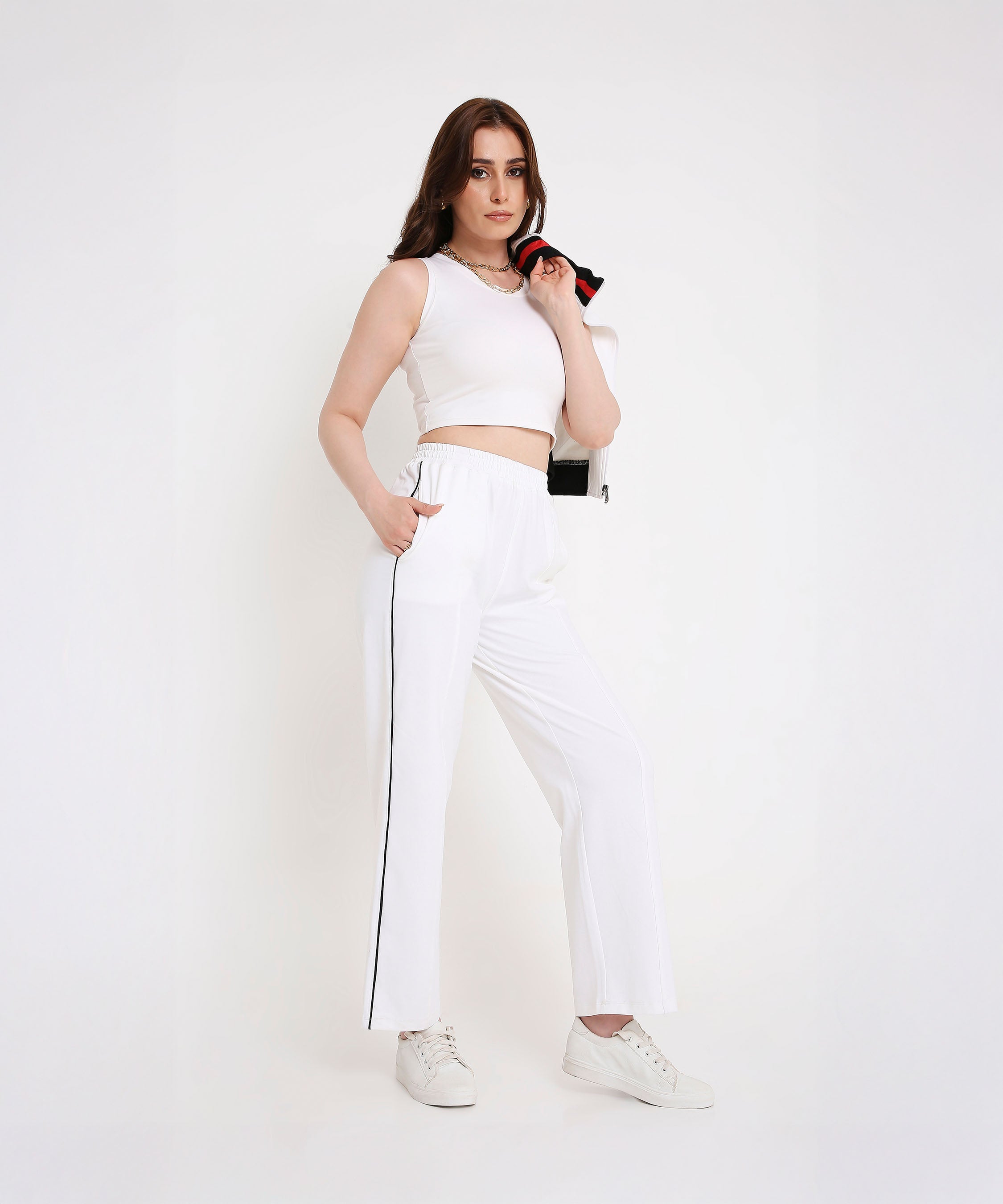 Confident woman in a sporty-chic style wears the Two Piece Bold Contrast White Tracksuit, featuring side stripes and a cotton-blend fabric, with the jacket draped over one shoulder.