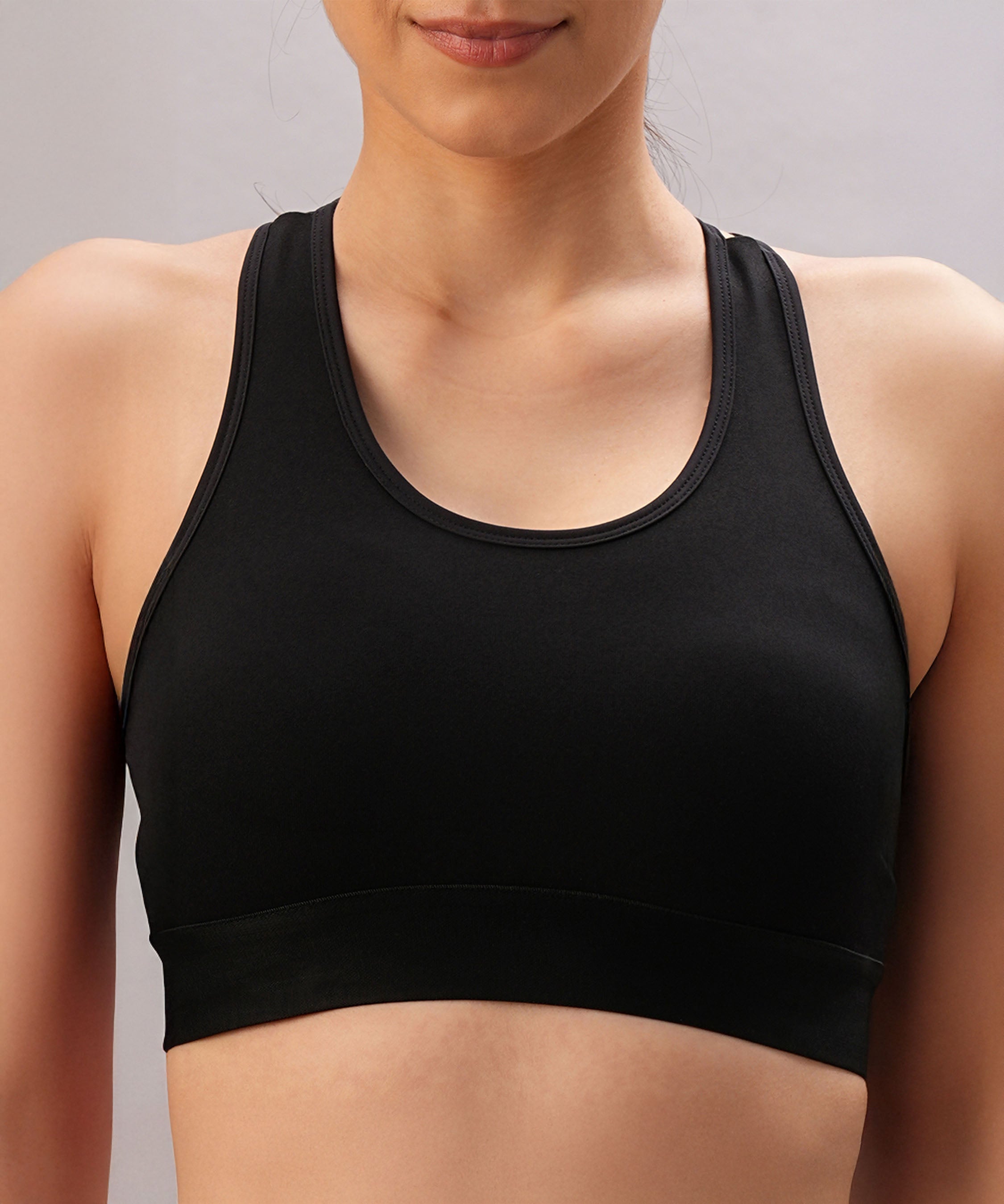 Model wears the Black Sports Bra with adjustable straps, shown from shoulders to waist against a neutral background.