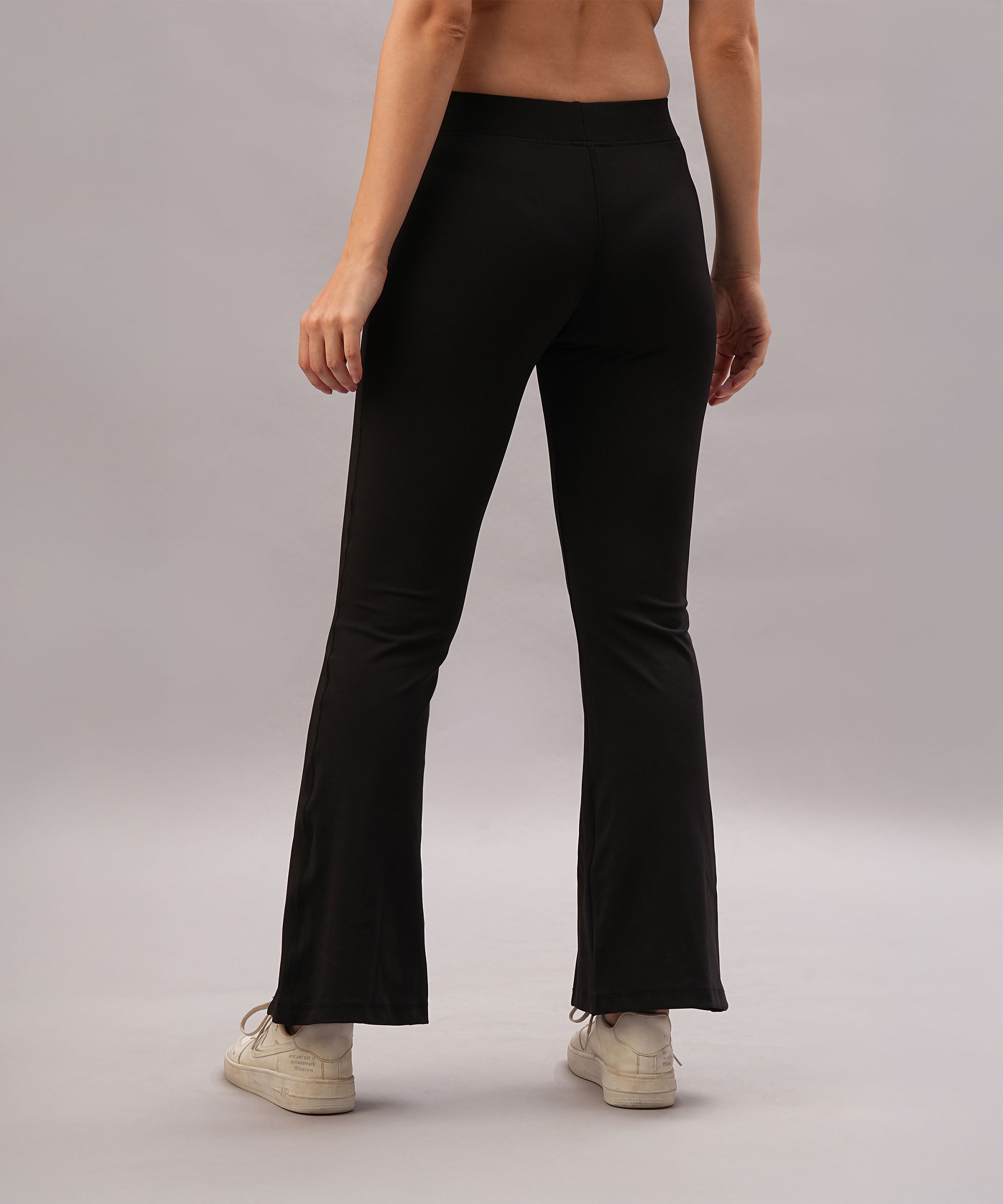 A person stands against a plain light gray background, wearing Black Slit Leggings and white sneakers.