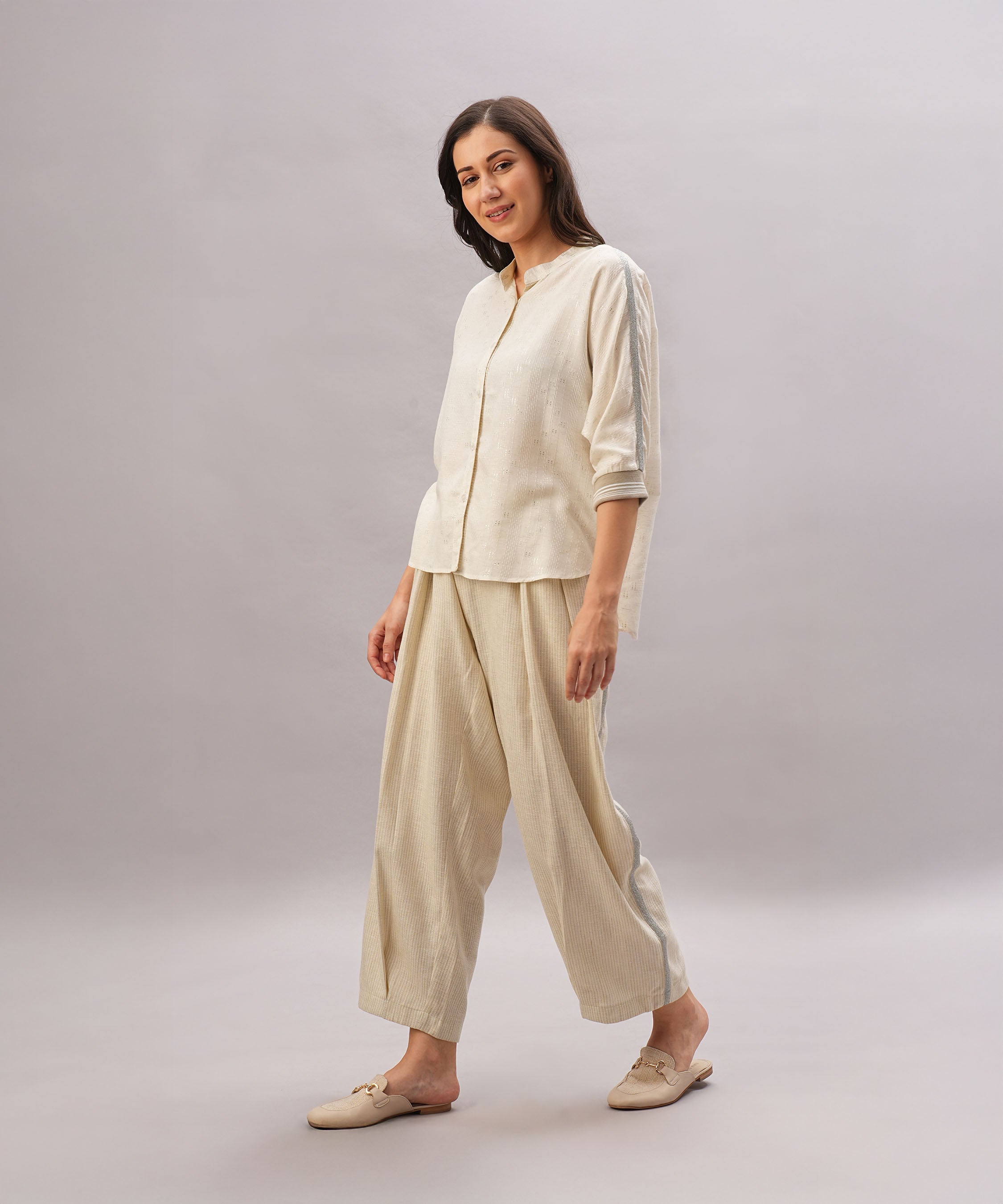 A woman wearing the Beige Linen Set with a relaxed fit smiles against a plain light gray background, showcasing the comfort and breathability of this linen outfit.