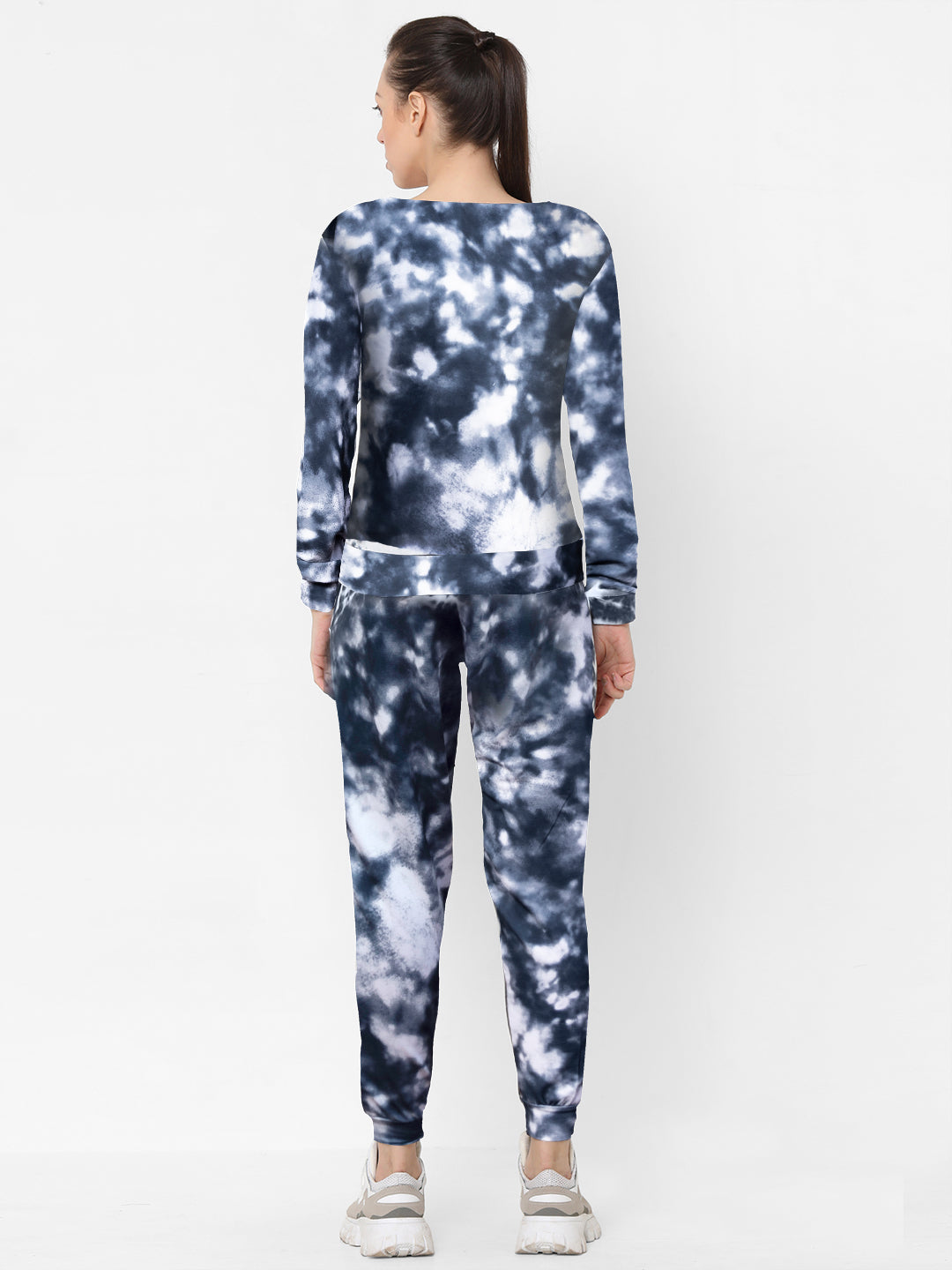 A woman stands with her back to the camera, wearing the Tie and Dye Tracksuit Set—blue and white joggers with a matching trendy sweatshirt—paired with white sneakers.