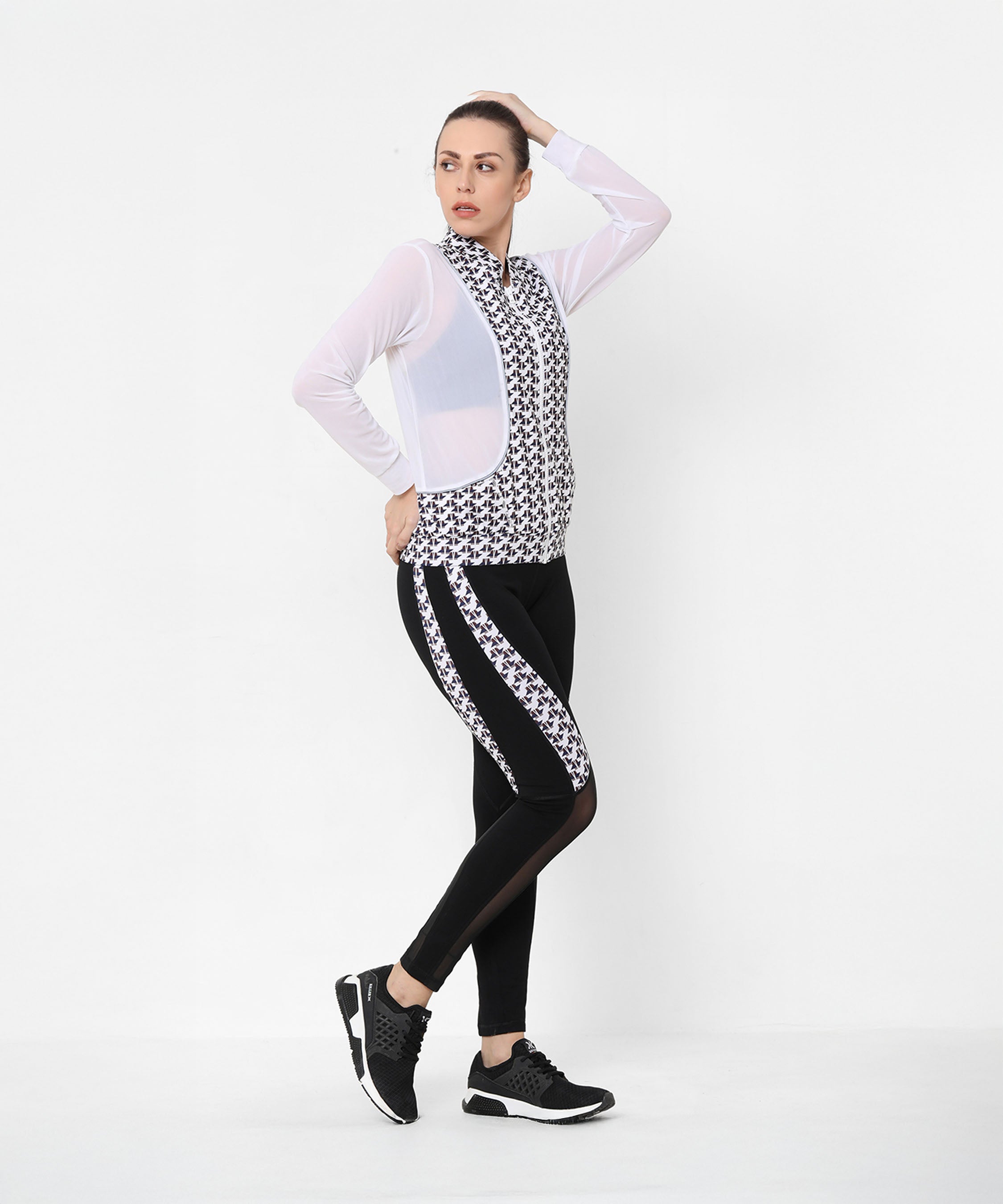A woman confidently poses with one hand on her hip and the other on her head, showcasing the Esther Jacket With Leggings trackset against a white background.