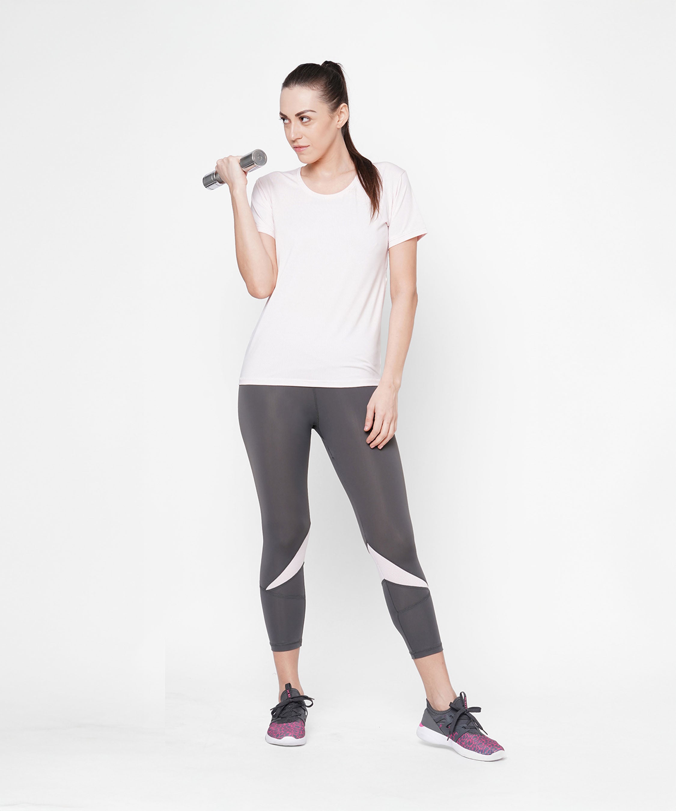 Woman in workout clothes wears Classic Capri in grey, featuring a thick waistband, and holds a dumbbell while standing against a plain white background for that fab fit look.