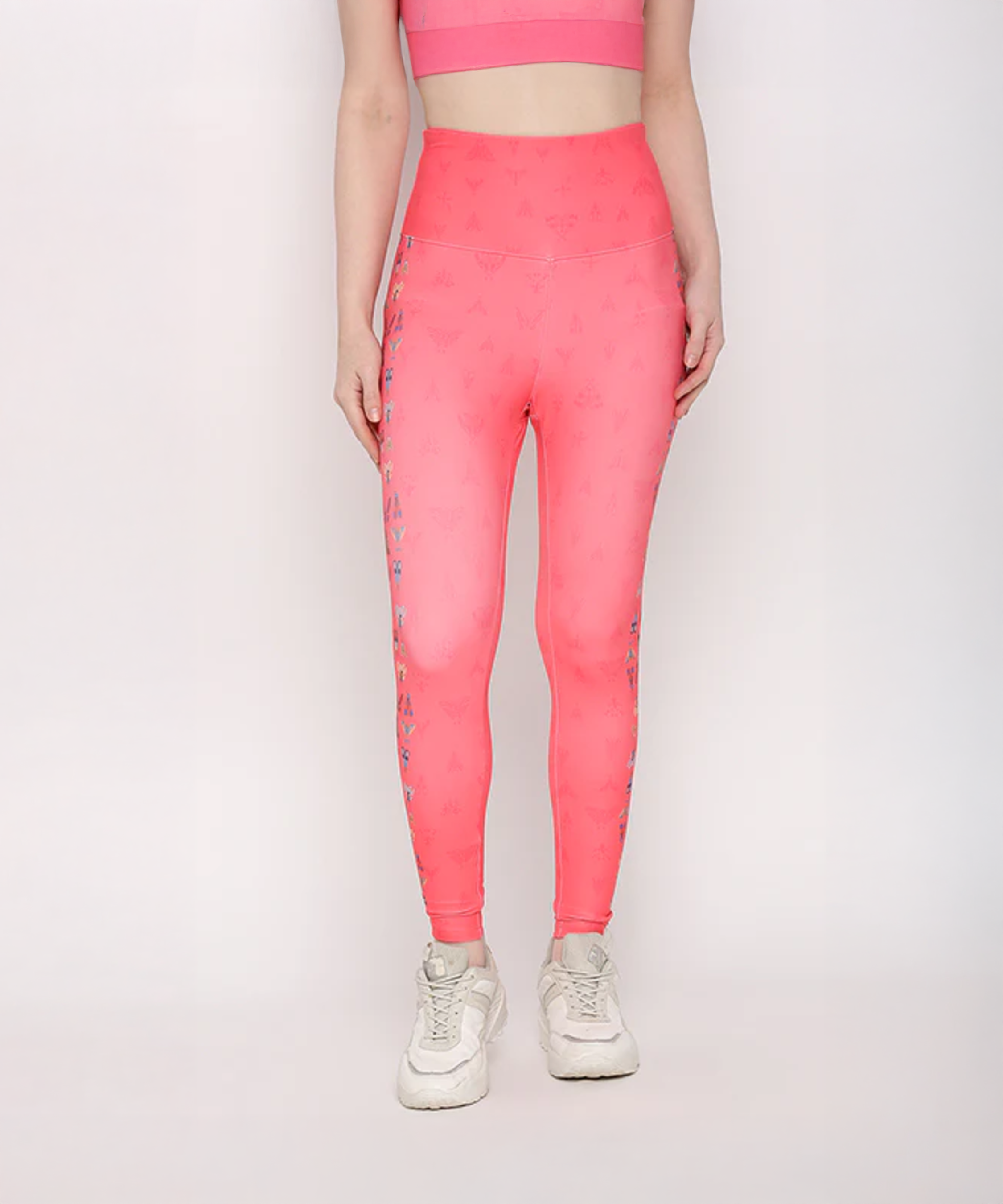 Person wearing Tuna Active Coral Pink Printed Leggings with a matching pink crop top and white sneakers, standing against a white background.