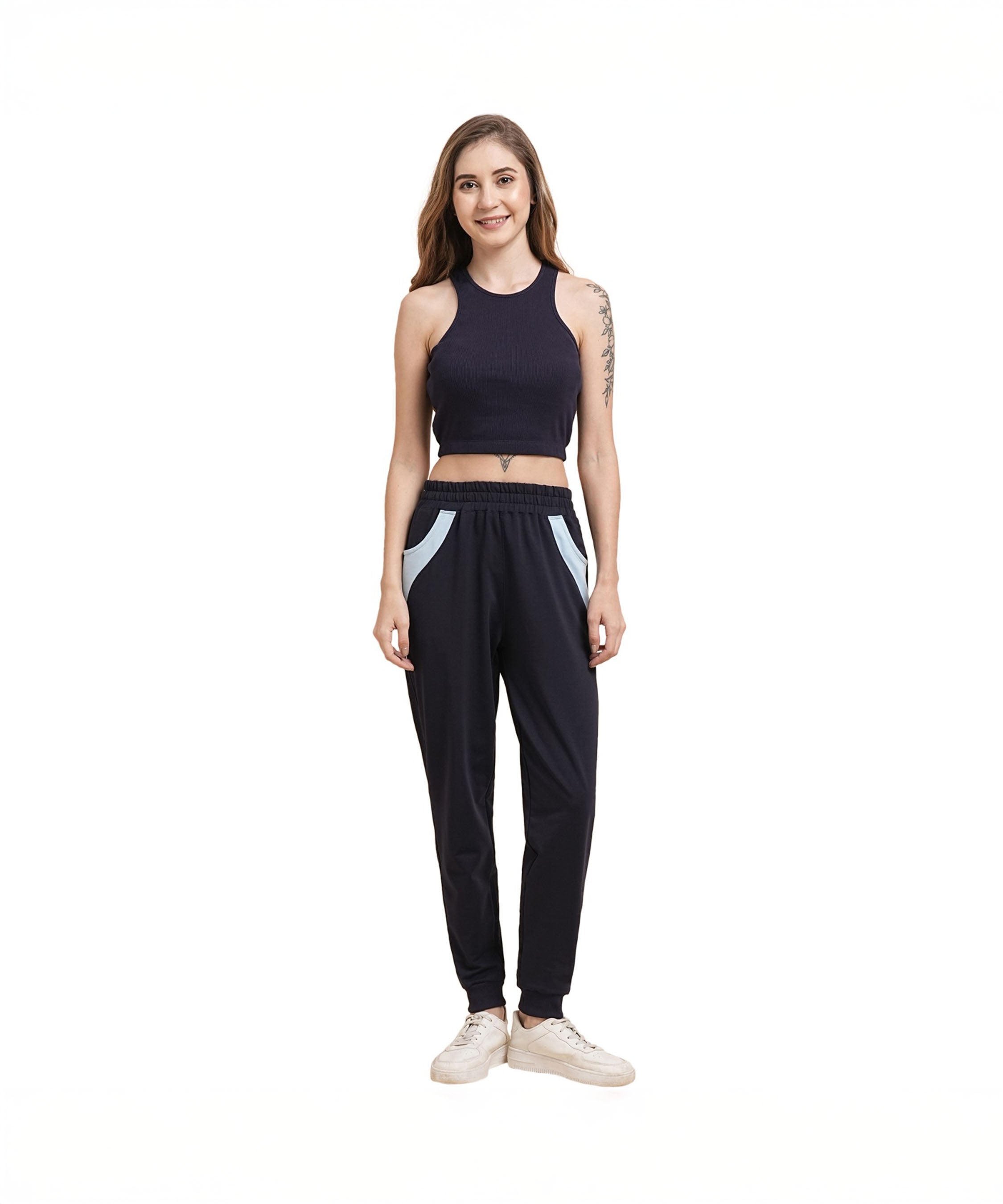 A woman stands and smiles against a white background, wearing a Navy Blue Crop Top paired with joggers and white sneakers.