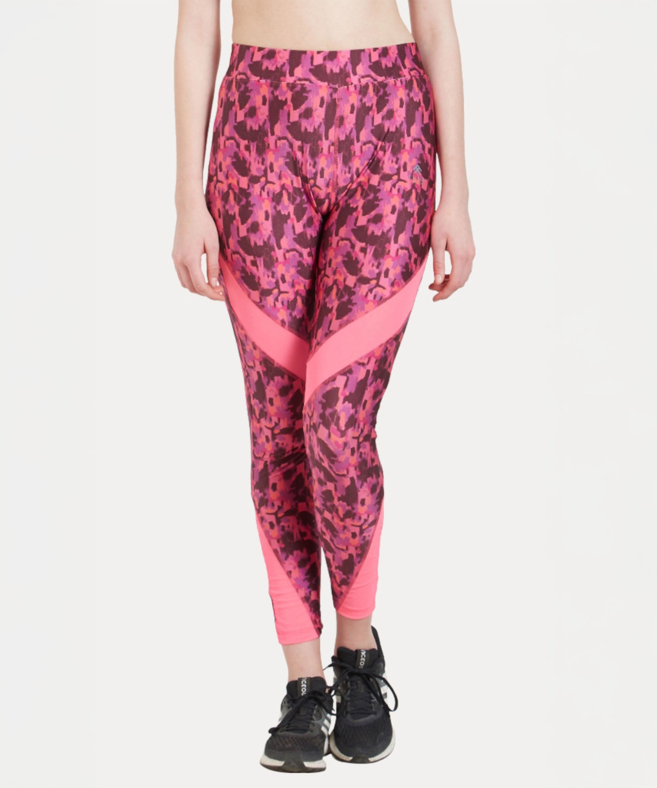 A woman models the Printed Slim Fit Track Pant LUSH, featuring a pink print and high-rise waistband, paired with black sneakers against a white background.