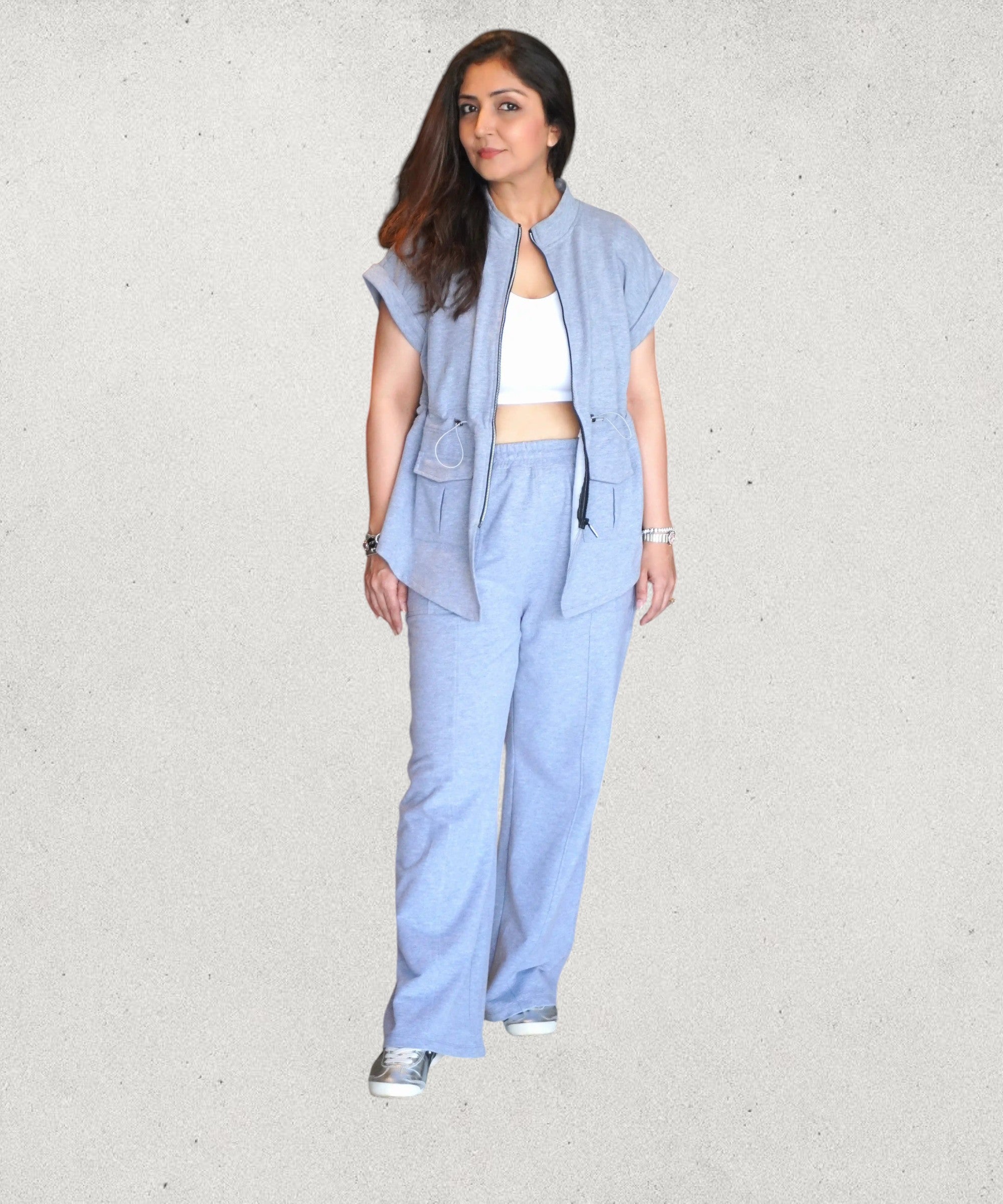 Tuna Active light blue zippered utility jumpsuit with wide legs and patch pockets, worn by a woman with a white crop top and sneakers.