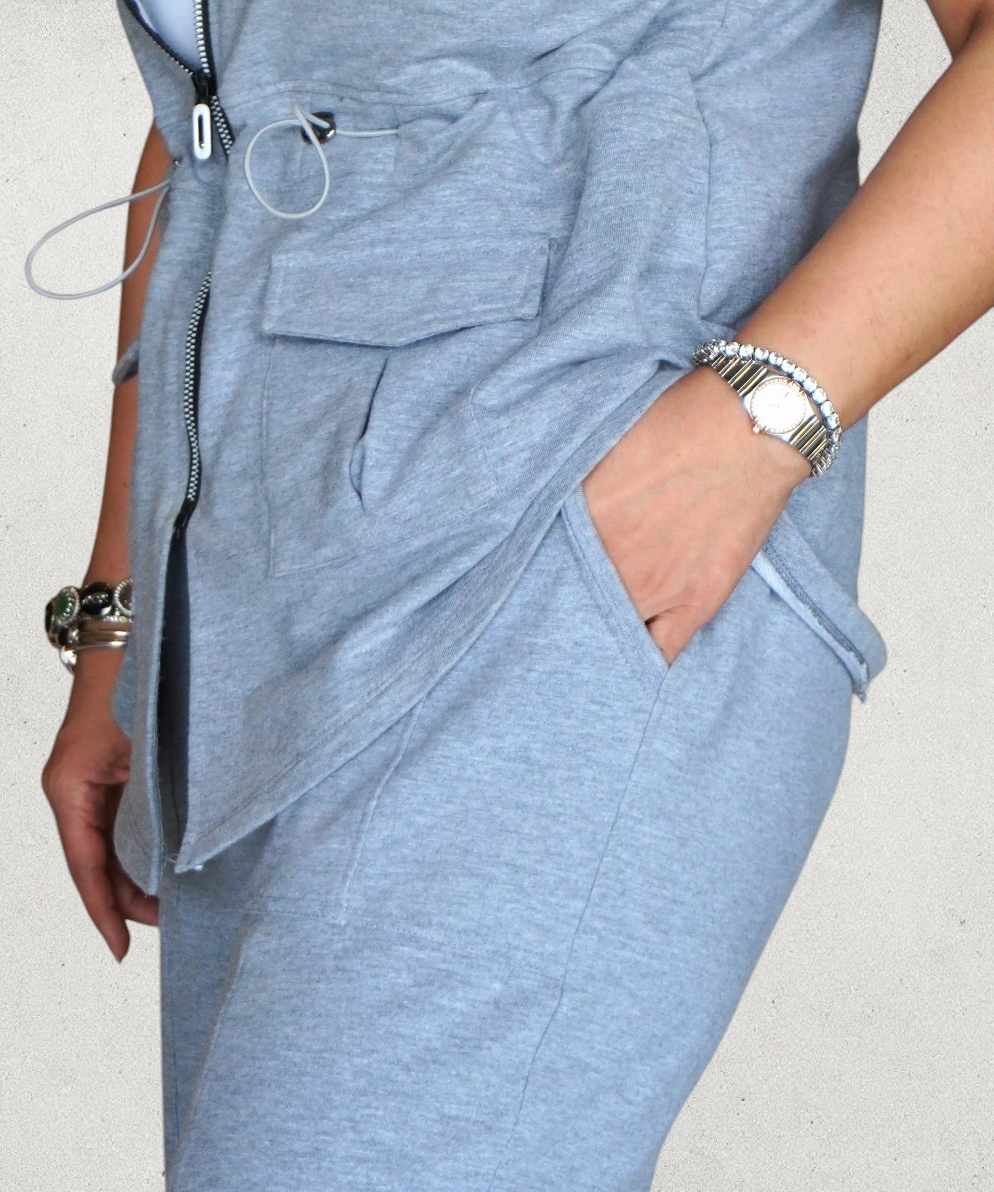 Tuna Active light blue zippered utility jumpsuit with patch pockets and wide legs. Model wears a silver watch.