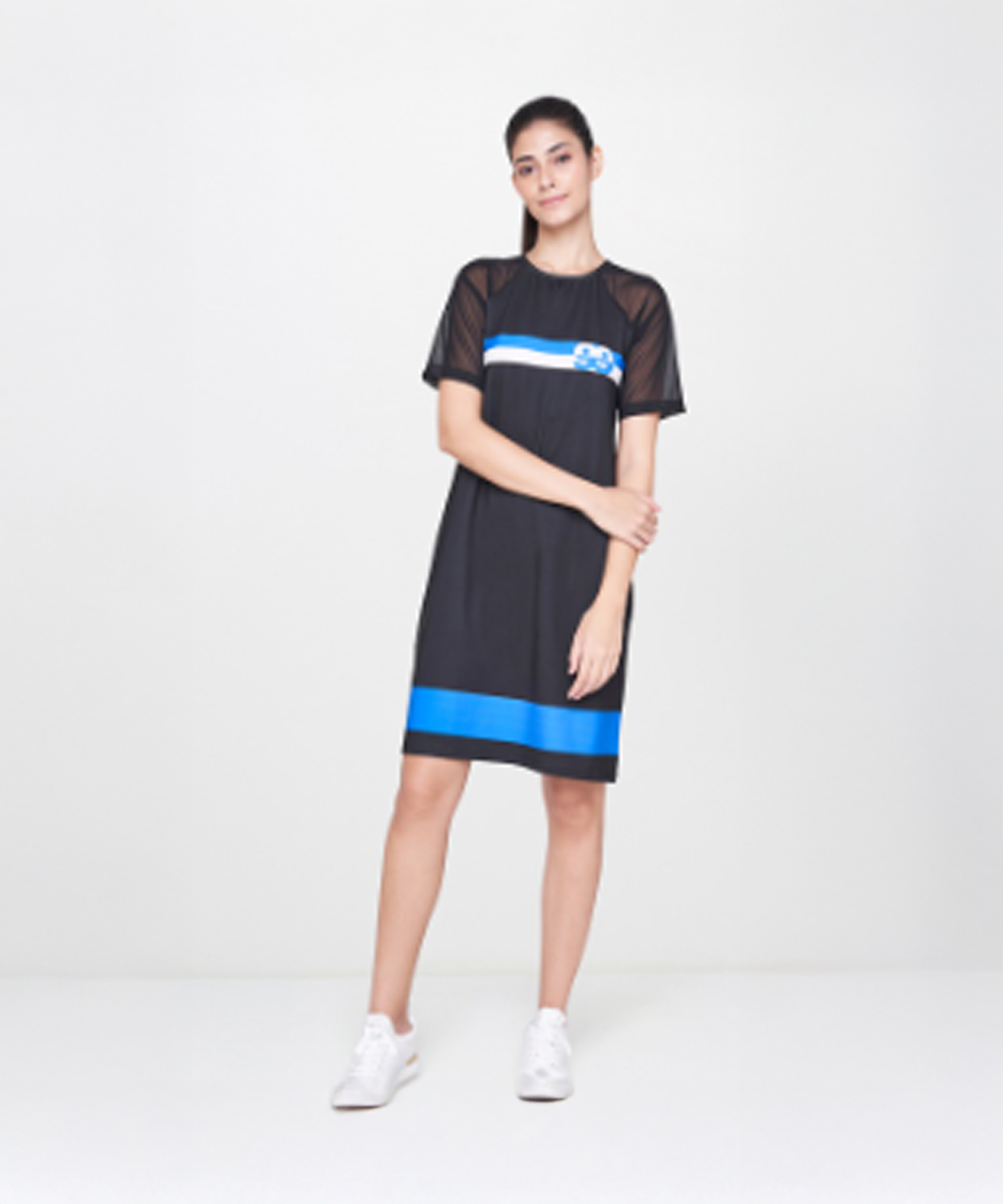 A woman wears the Black Sporty Dress and completes her look with crisp white sneakers.