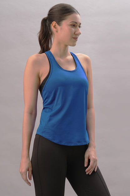 A woman models the Blue Racer Back Top with black pants against a plain light background, glancing to the side for a sporty, stylish vibe from the latest activewear collection.