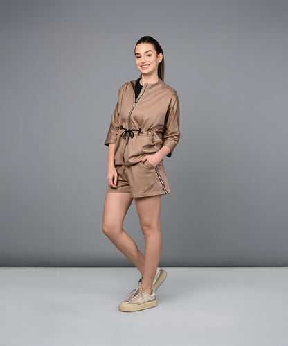 A woman stands smiling, wearing the Zipped Neutral Jacket Shorts Set with sneakers against a plain gray background.