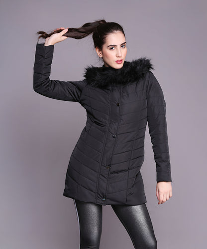 A woman strikes a pose against a plain background, holding her ponytail while wearing the Black Fur Collar Long Puffer Jacket With Button and Zip Details.