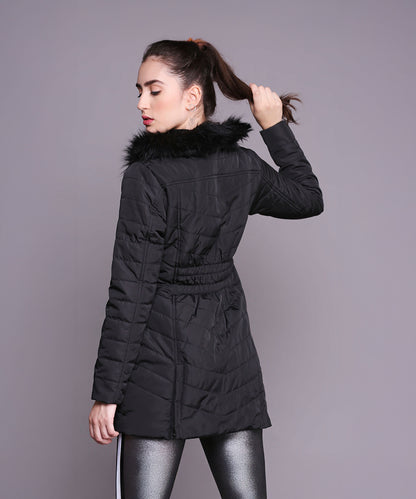 A woman faces away, holding her ponytail, wearing the Black Fur Collar Long Puffer Jacket With Button and Zip Details against a gray background.