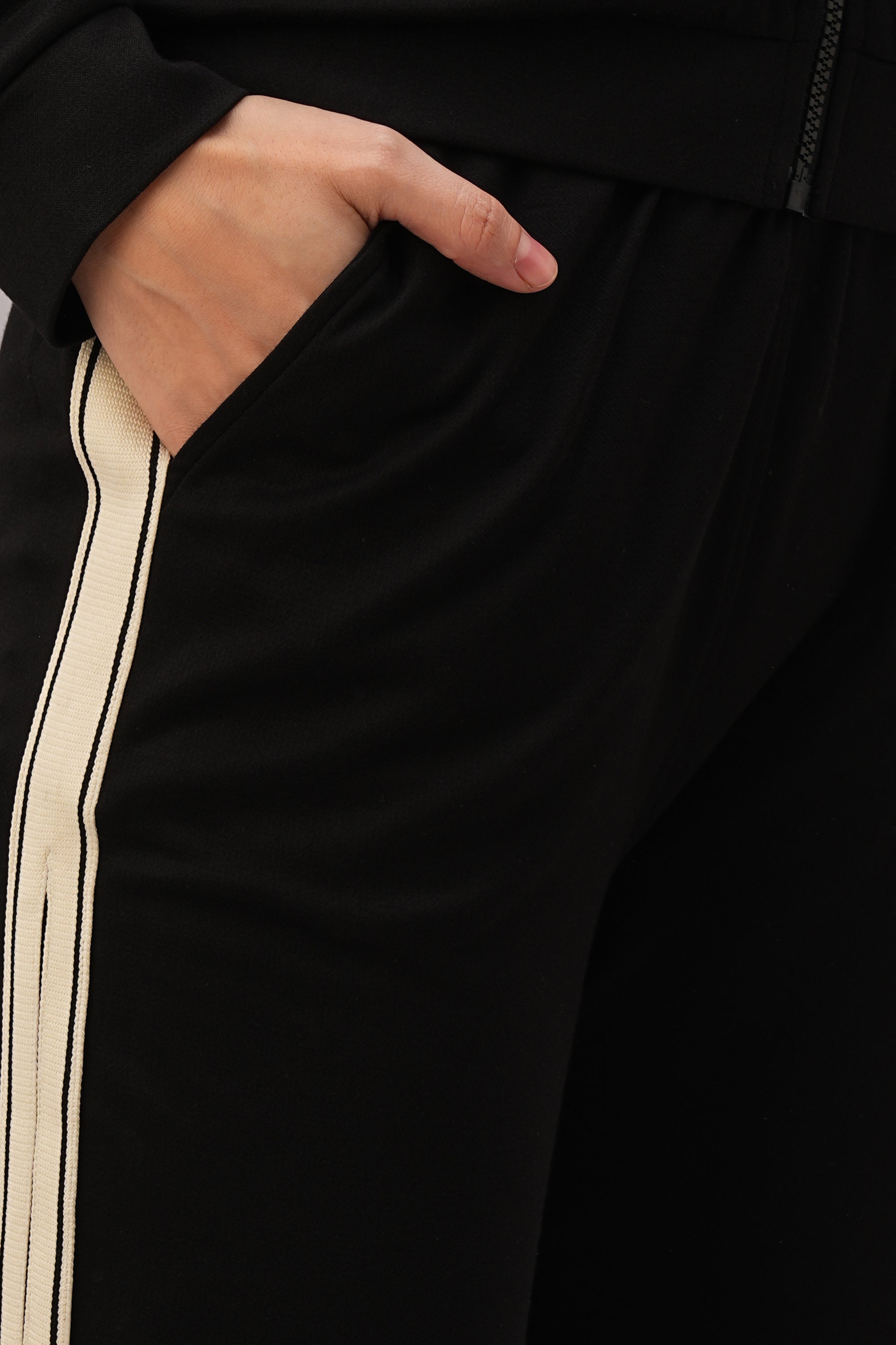 Close-up of a hand in the pocket of Black Co-Ord Set pants with a white side stripe, ideal for pairing with your favorite top or styling as part of a coordinated outfit.