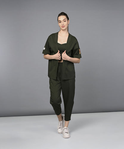 Woman in a Military Green Open Jacket & Yoga Pants with Bustiere set and white sneakers stands against a plain gray background.