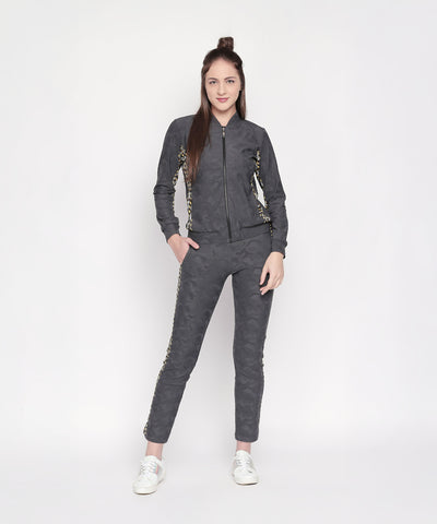 Woman in an Active Wear Printed Jacket in Grey from Tuna London, featuring a dark gray polyester blend with patterned sides, standing and smiling against a plain white background.