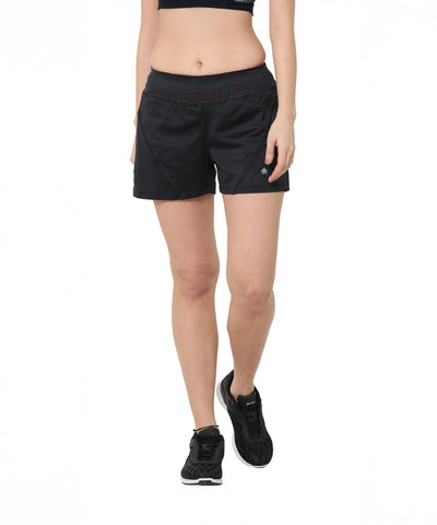 A woman wearing Black Shorts, a black crop top, and black sneakers stands against a white background. The shorts are made from breathable fabric.