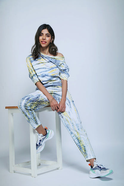 A woman smiles while sitting on a stool, wearing the One Side Off-Shoulder + Yoga Pants set in Yellow & Grey against a plain light background.