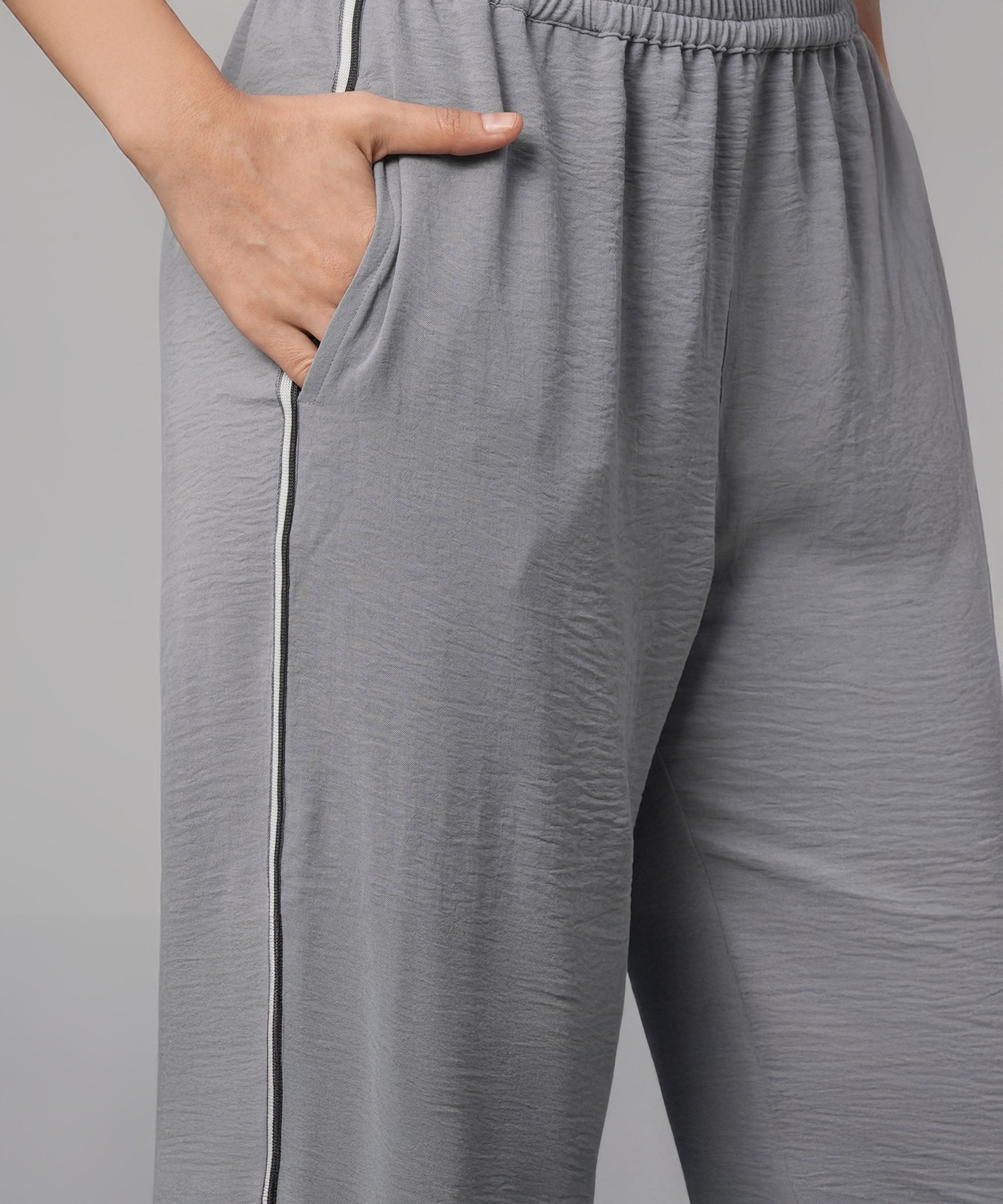 Person wearing the Grey Tie Up Top with Loose Pants Cord Set, featuring loose gray pants with a side stripe and pockets, shown from waist to mid-thigh.