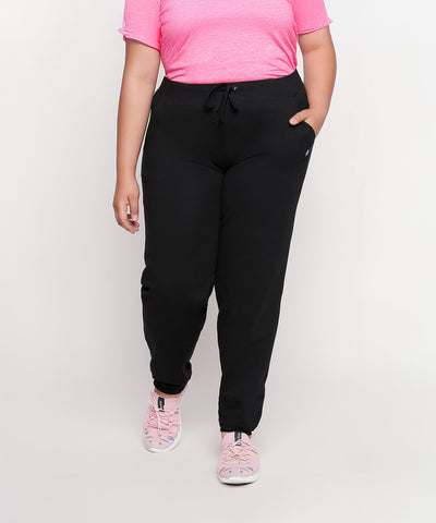 Person wearing a pink shirt, Classic Joggers - Plus Size 02, and pink sneakers stands against a plain background.