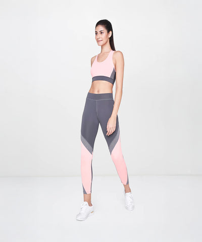 Woman in pink and gray sportswear poses confidently in a studio, highlighting her high-waisted Grey Leggings against a plain light background.