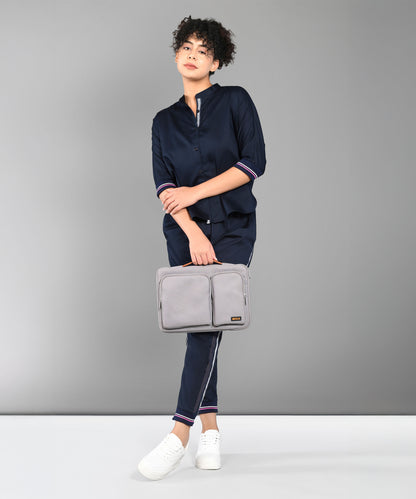 A person wears the Accented Set in navy blue cotton, paired with white shoes and holding a gray bag, standing before a plain gray background.
