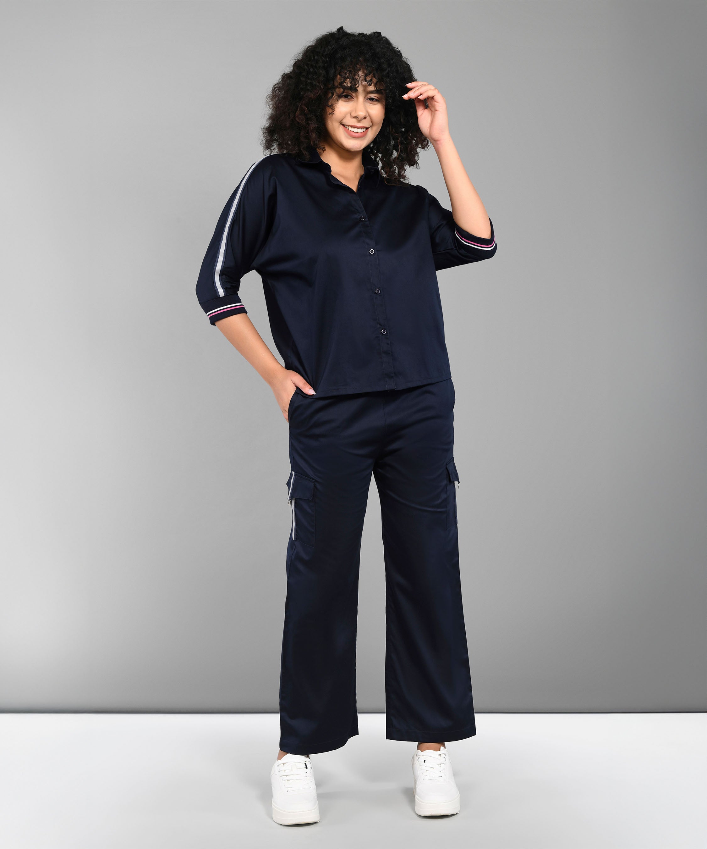 Person with curly hair wearing the Navy Blue Chic Set and white sneakers, standing and smiling.