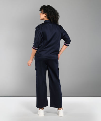 A person wearing the Navy Blue Chic Set with track pants and white sneakers stands facing away against a plain gray background.