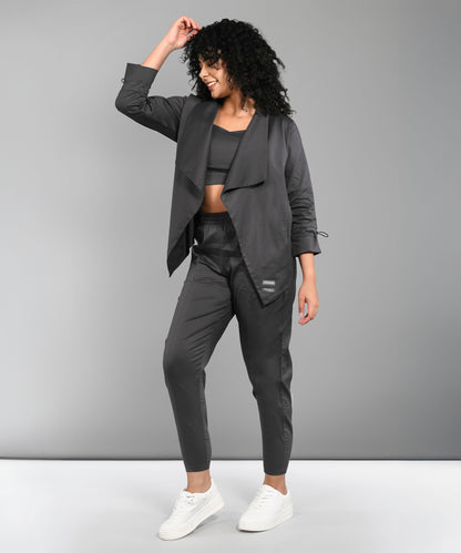 Model wearing the Timeless Brilliance Grey Co-ord Set with Crop Top, posing and smiling in white sneakers against a gray background.