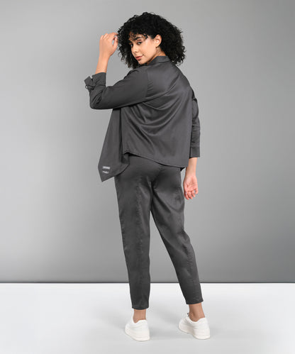 A woman with curly hair stands and looks over her shoulder, wearing the Timeless Brilliance Grey Co-ord Set with Crop Top and white sneakers.
