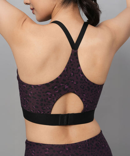 A woman wears the Pink Animal Print Sports Bra, featuring a keyhole back and clasp. This stylish bra delivers both flair and comfort for active days, perfect for those who love standout workout wear.