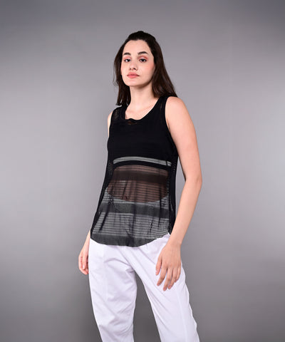 Woman wears the Tuna Active Black Netted Tank Top with white pants, standing against a plain gray background.