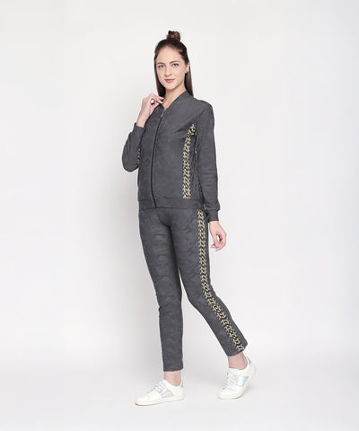 Woman wearing an Active Wear Printed Jacket in Grey, featuring a gold pattern on the sides, stands smiling against a white background.