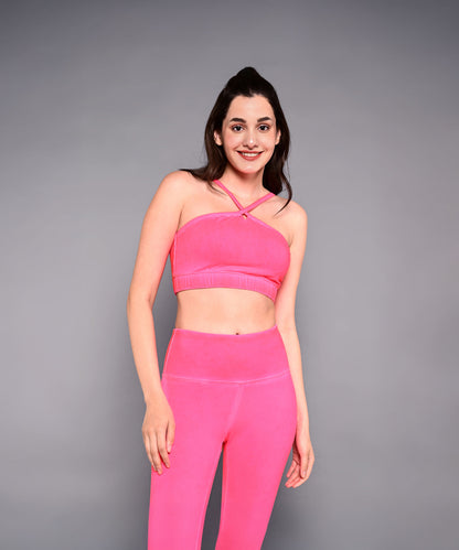 Woman wearing a Neon Pink Sports Bra, standing and smiling against a plain gray background.