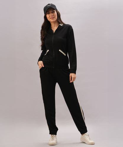 A woman wearing the Black Co-Ord Set pairs it with white sneakers and a black cap, smiling against a plain background to showcase this stylish coordinated outfit.