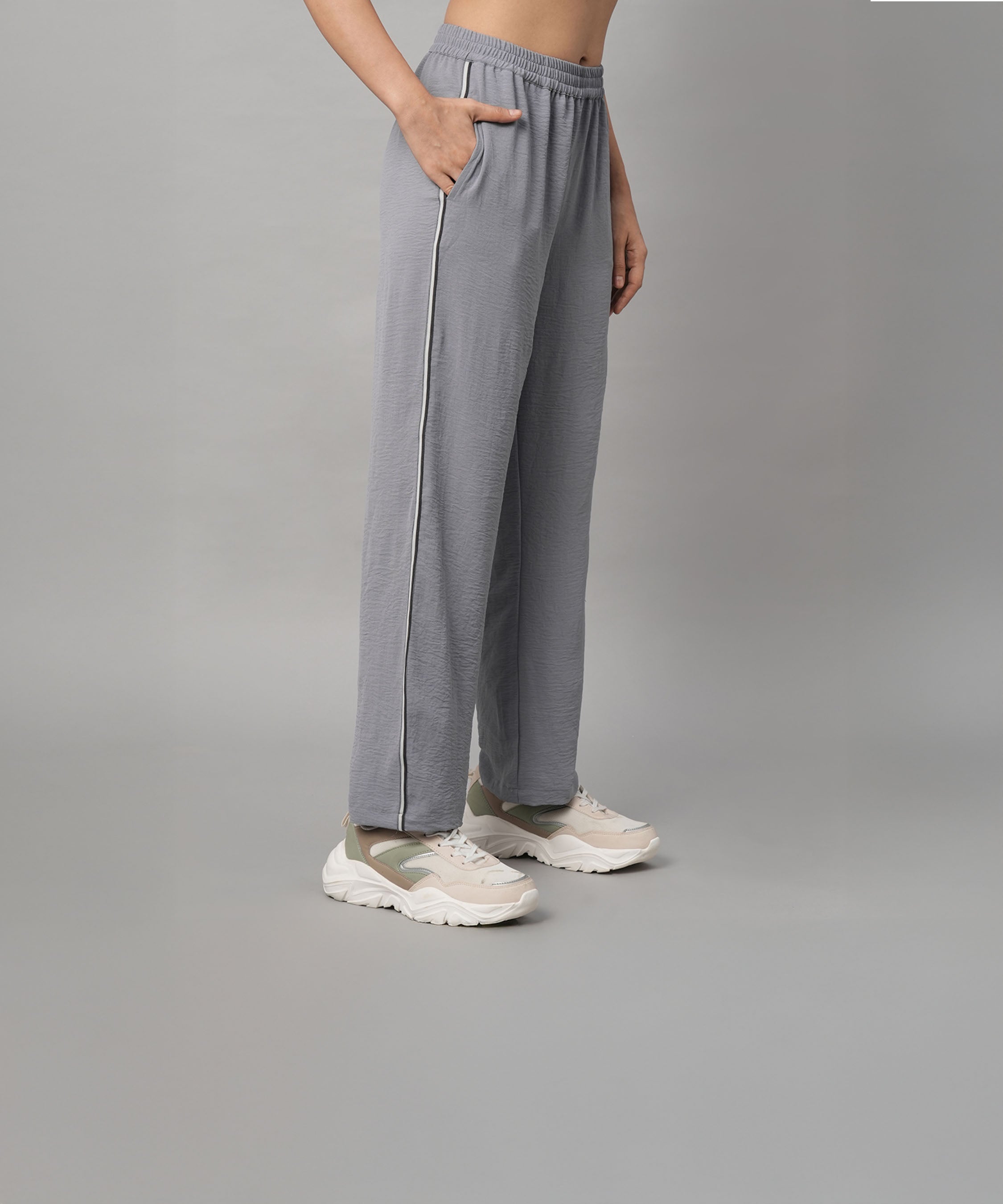 Wearing the Grey Tie Up Top with Loose Pants Cord Set and white sneakers, the person stands against a plain background.