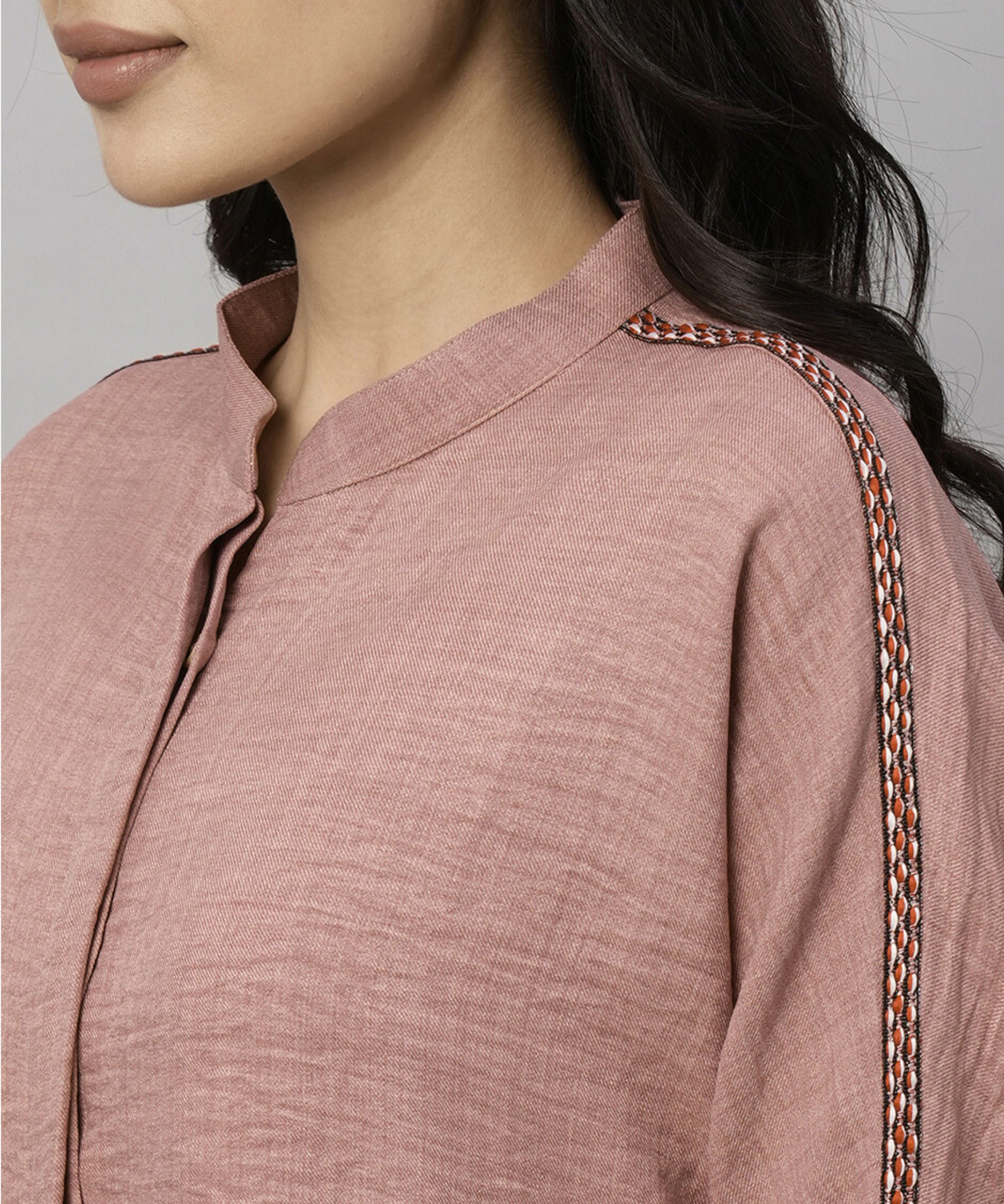 Woman wears the Vintage Pink Loose Shirt and Tie Up Pant Cord Set in 100% cotton, featuring a textured kurta with braided sleeve detail; shown from the shoulders up.