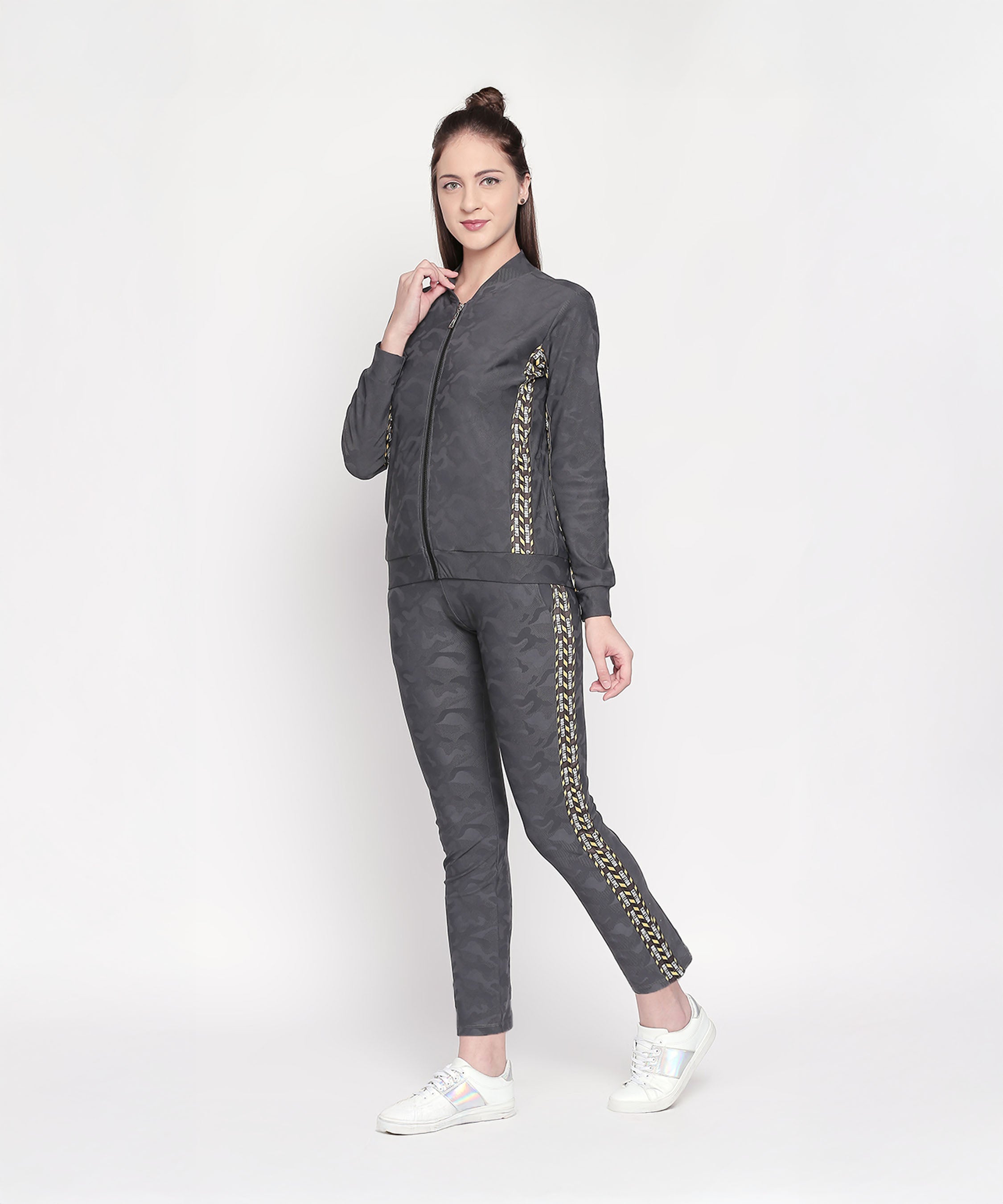 Woman wearing a Camouflage Print Tracksuit with a V-neck collar jacket and elasticated track pants featuring gold detailing, standing and smiling against a plain white background.