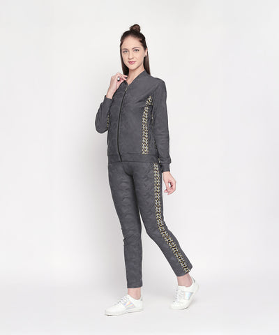 Woman wearing a Camouflage Print Tracksuit with a V-neck collar jacket and elasticated track pants featuring gold detailing, standing and smiling against a plain white background.