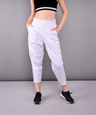 Woman in black crop top and Pleated Yoga Pant With Smocked Waistband, featuring white pleats and pockets, standing against a gray background.