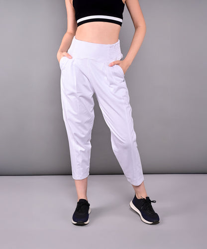 Woman in black crop top and Pleated Yoga Pant With Smocked Waistband, featuring white pleats and pockets, standing against a gray background.