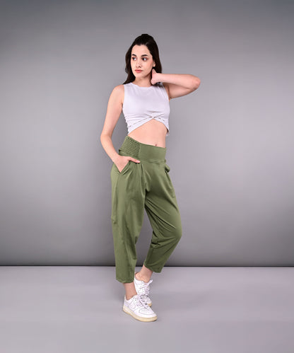 Woman wears green Pleated Yoga Pant With Smocked Waistband, featuring pleats and a high waist, paired with a gray sleeveless crop top and white sneakers.