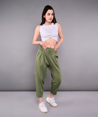 A woman models the White Twisted Crop Top with green pants and white sneakers, posing against a plain gray background.