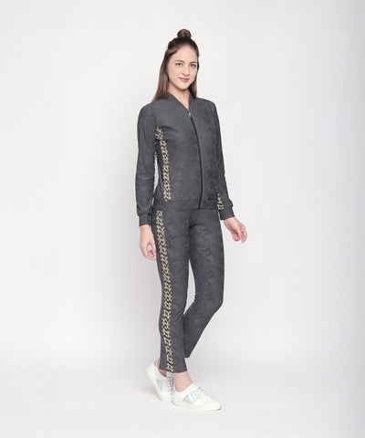 Woman in a grey "Active Wear Printed Jacket" by Tuna London with yellow side details, standing and smiling against a white background.
