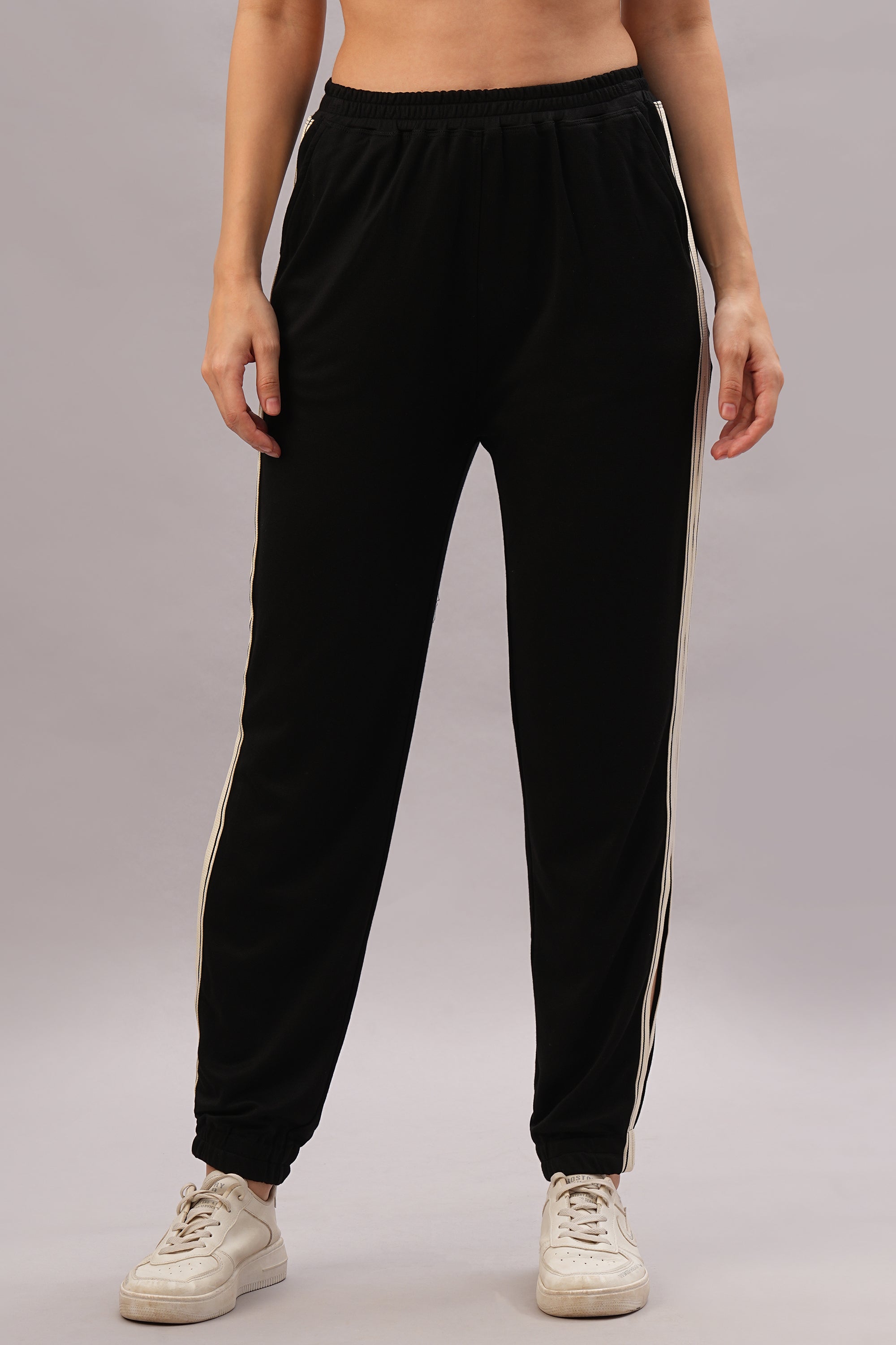 Model in the Black Co-Ord Set stands on a gray background, pairing it with white sneakers for an effortlessly stylish and coordinated look.