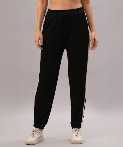 A person models the Black Co-Ord Set made from soft cotton lycra, featuring black track pants with white side stripes, paired with white sneakers against a plain background.
